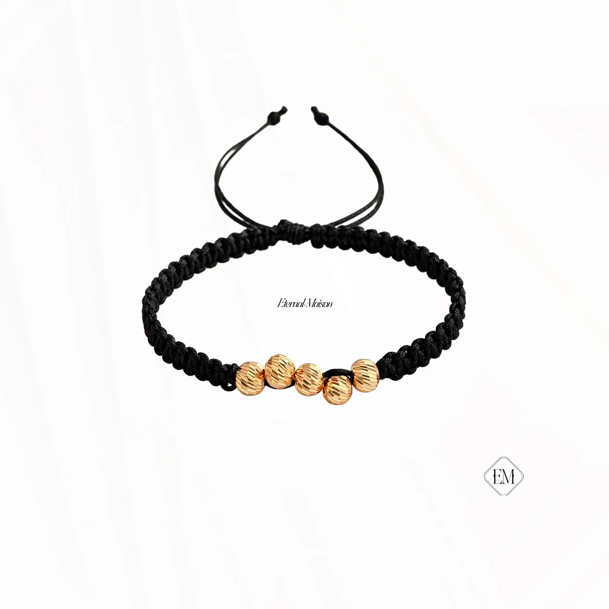 Pulsera de macramé negro con cinco balines diamantados en oro, sobre fondo blanco.