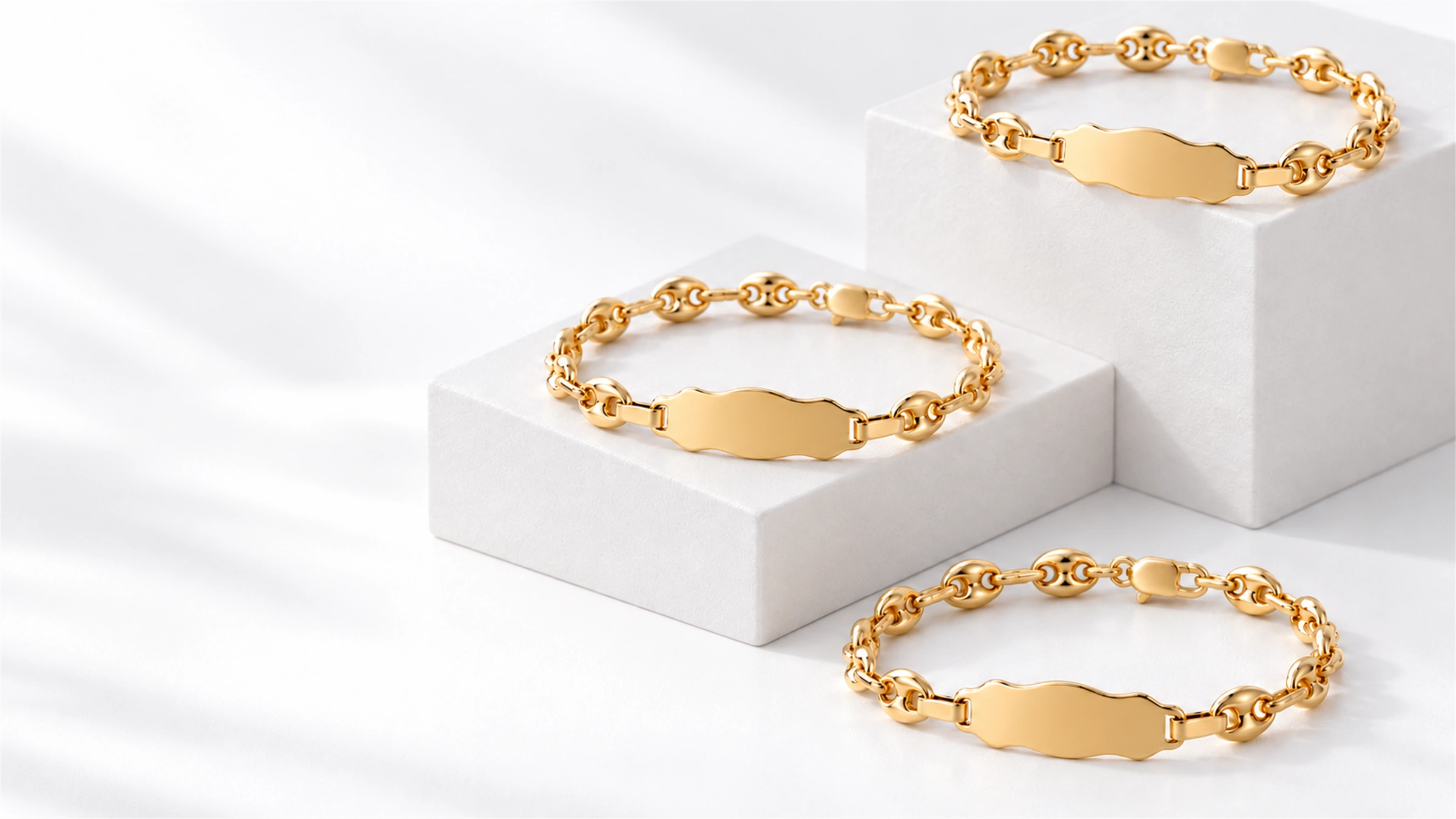 Tres esclavas de oro sobre cubos blancos, con placas para personalizar