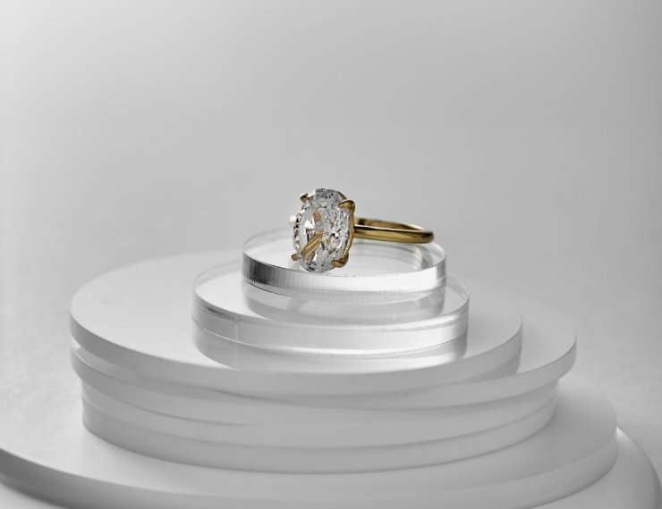 Anillo de compromiso de oro con diamante sobre pedestal, estilo editorial elegante