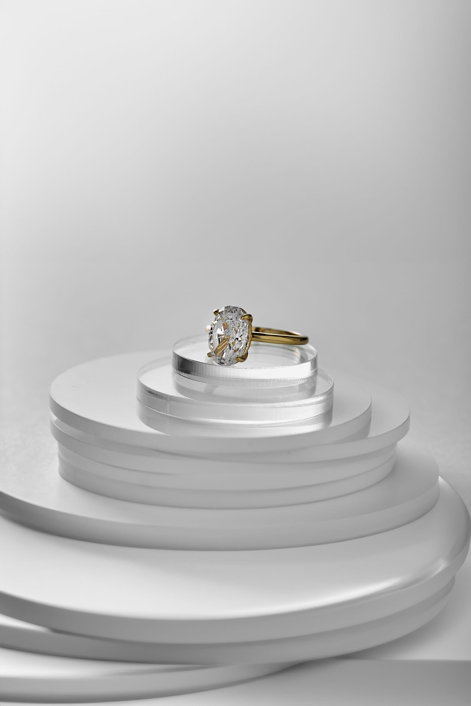 Anillo de compromiso de oro con diamante sobre pedestal, estilo editorial elegante