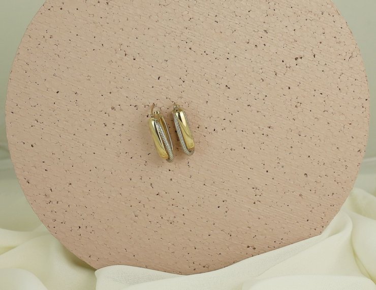Aretes dorados minimalistas sobre superficie neutra, estilo editorial