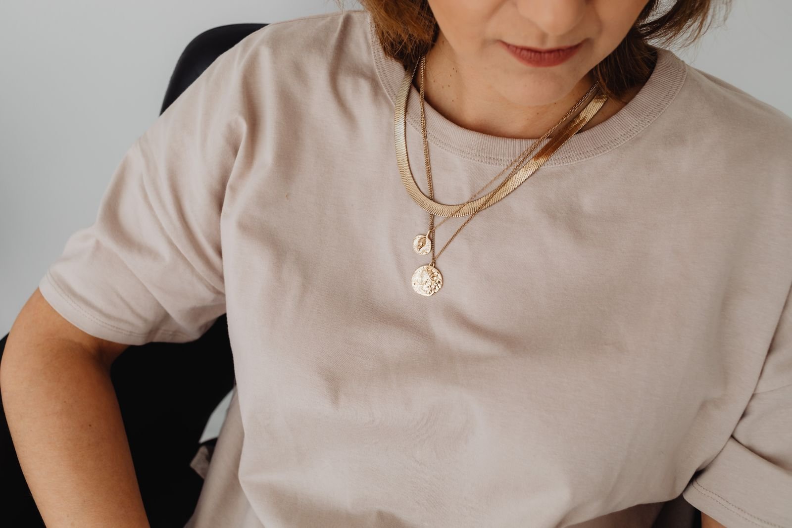 Mujer con collares de oro de distintos largos combinados sobre camisa clara