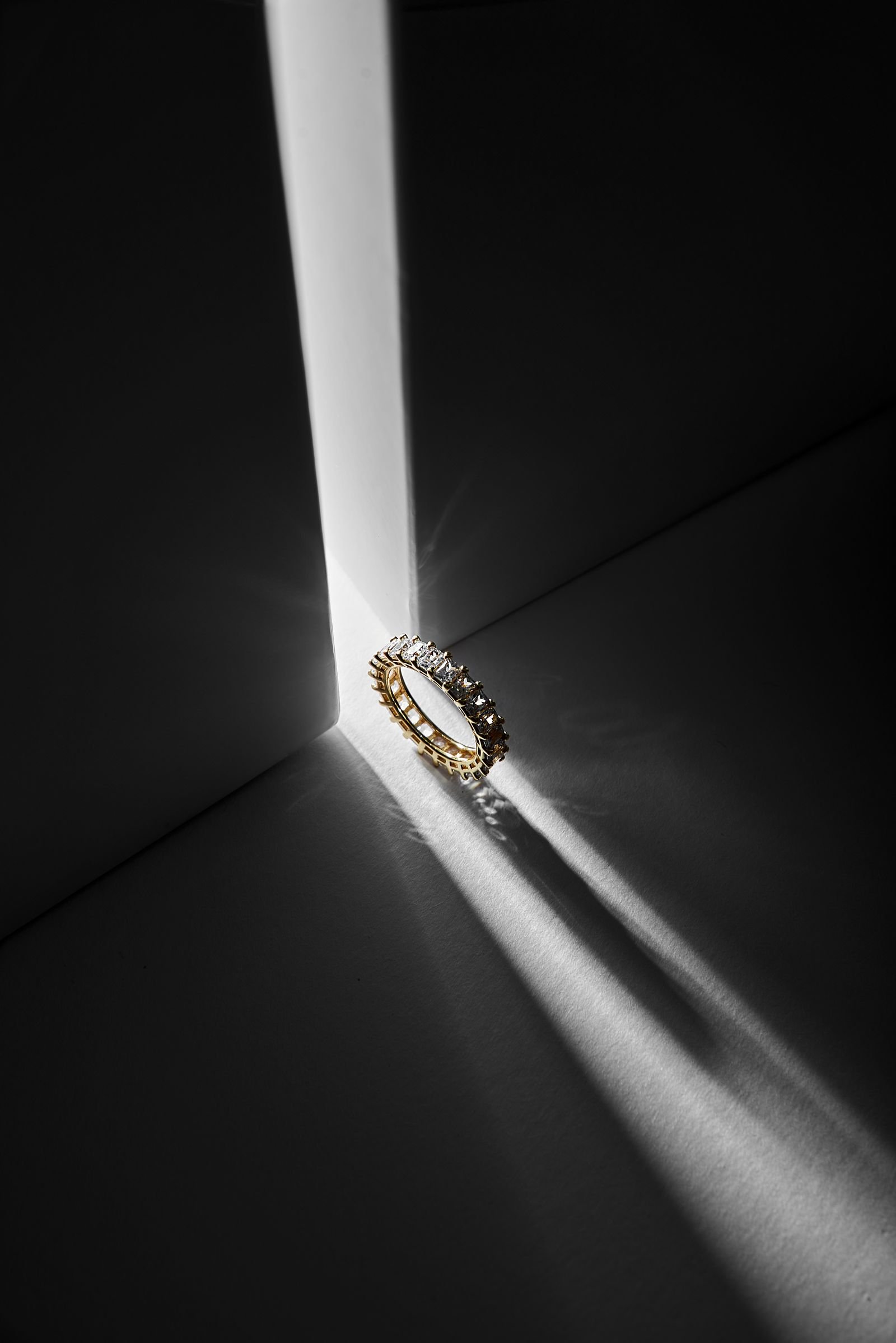 Anillo de diamante y oro 18K con luz dramática, estilo editorial