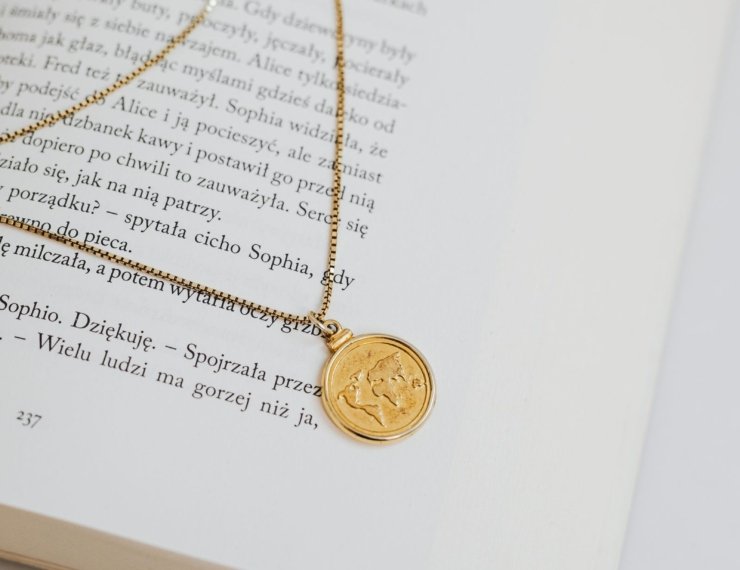 Dije de moneda en collar de oro 18K, composición editorial sobre libro