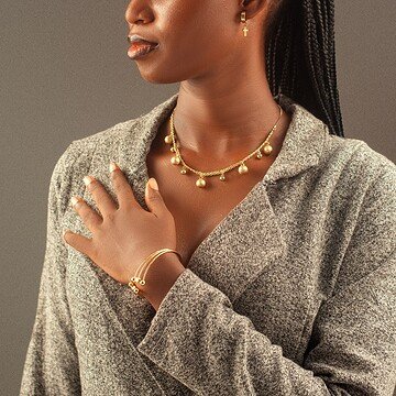 Mujer con trenza larga y accesorios de oro, retrato en estudio.
