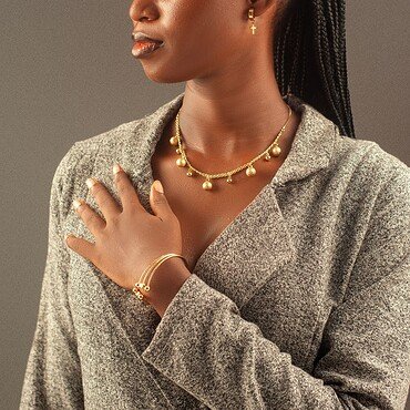 Mujer con trenza larga y accesorios de oro, retrato en estudio.