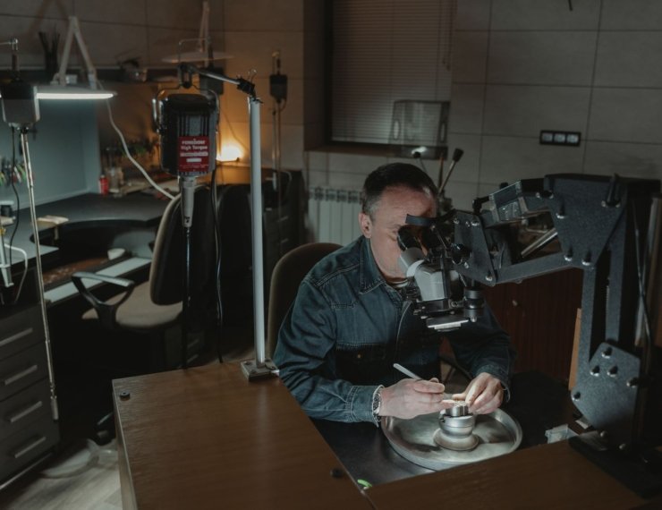 Joyero verificando piezas de oro en laboratorio con equipo especializado