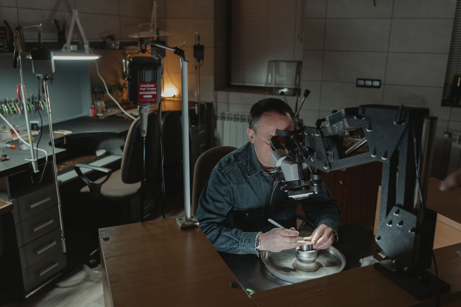 Joyero verificando piezas de oro en laboratorio con equipo especializado