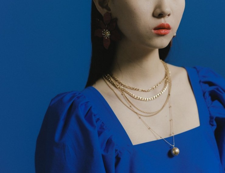 Modelo con collares de oro en capas, distintos largos, estilo editorial elegante