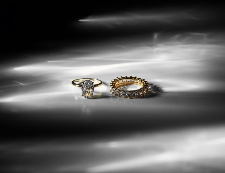Dos anillos de oro y diamantes sobre superficie reflectante, estilo editorial de lujo
