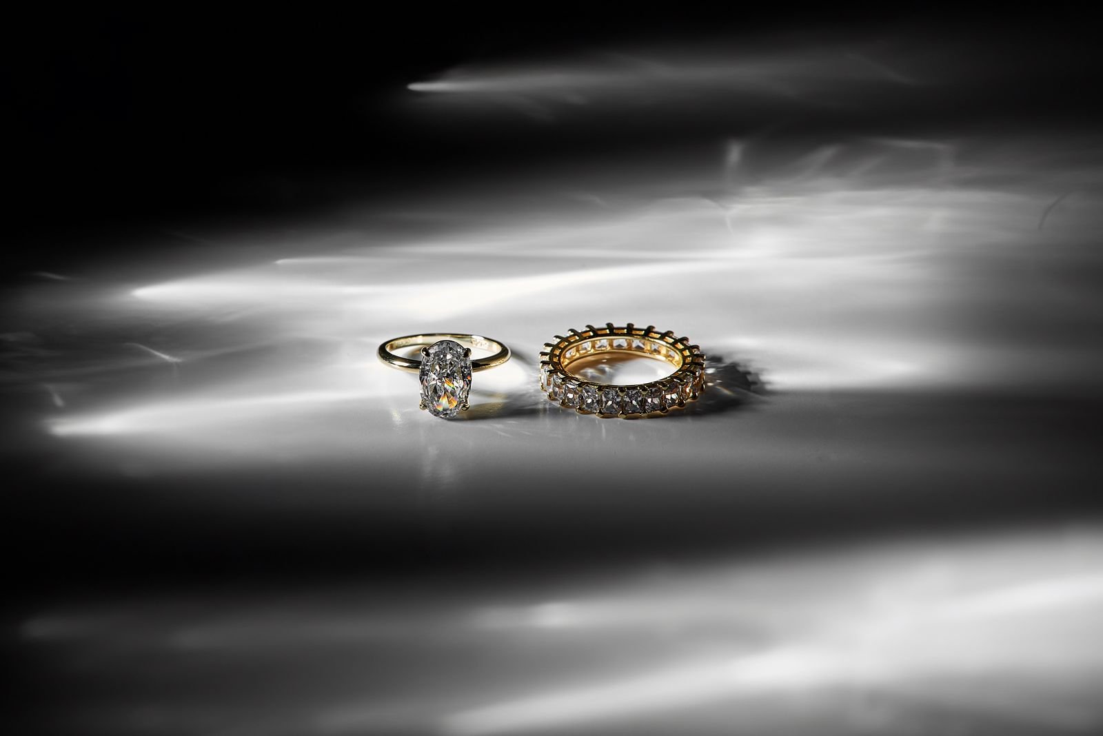 Dos anillos de oro y diamantes sobre superficie reflectante, estilo editorial de lujo