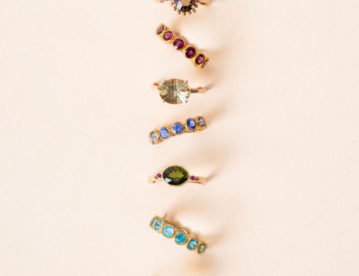 Colección de anillos de oro 18K con piedras de colores, composición editorial