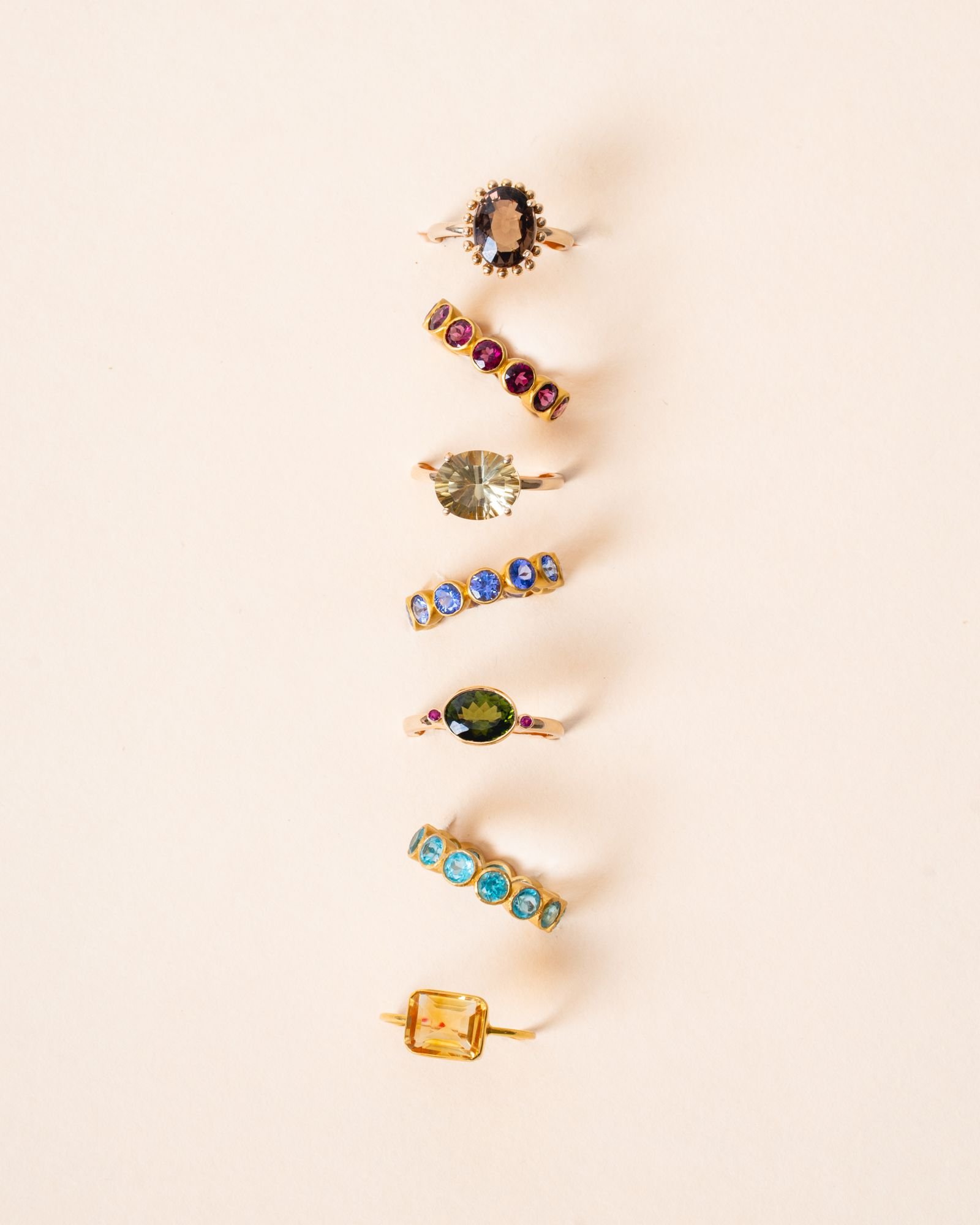 Colección de anillos de oro 18K con piedras de colores, composición editorial
