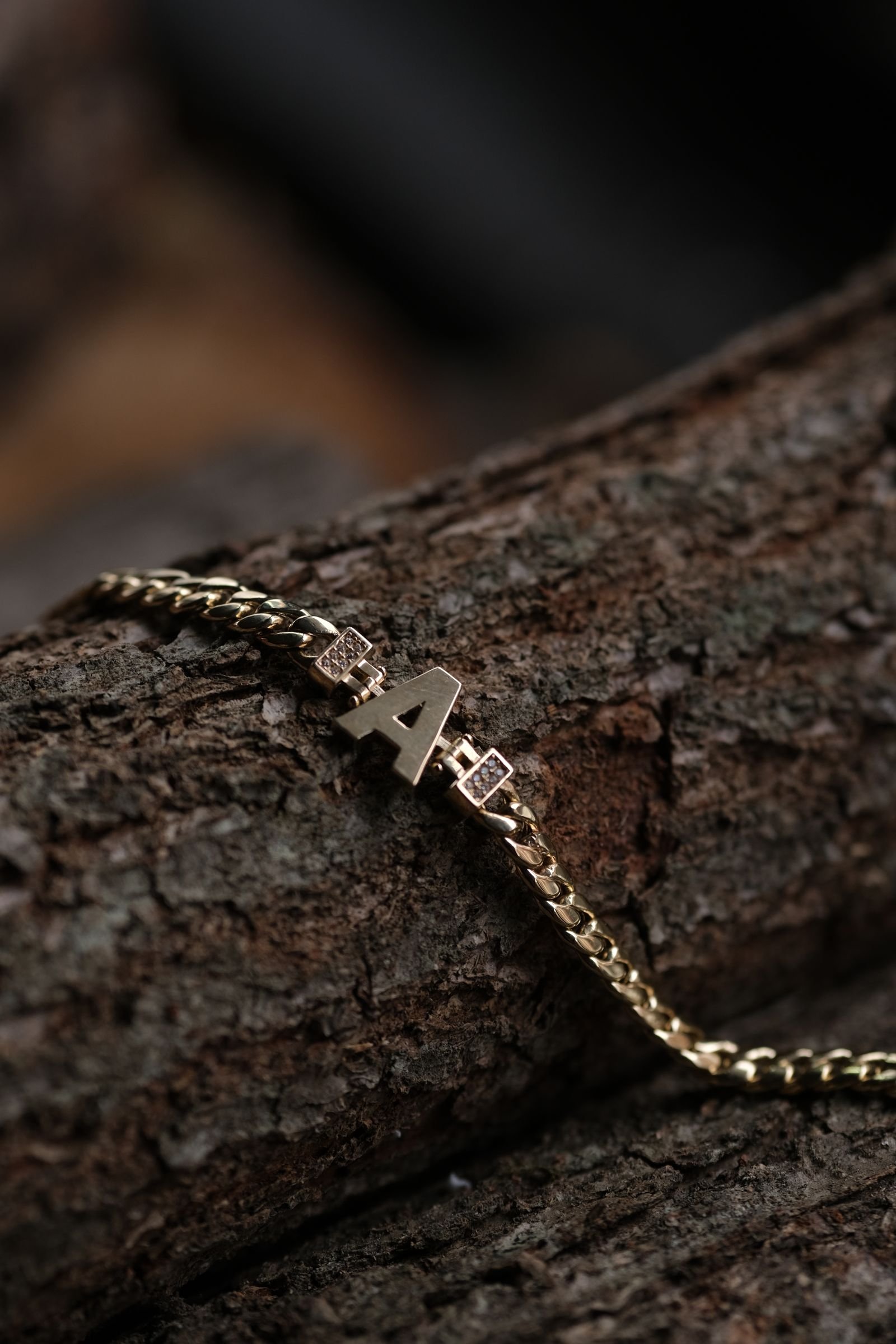 Detalle de pulsera de oro 18K con inicial personalizada, estilo editorial